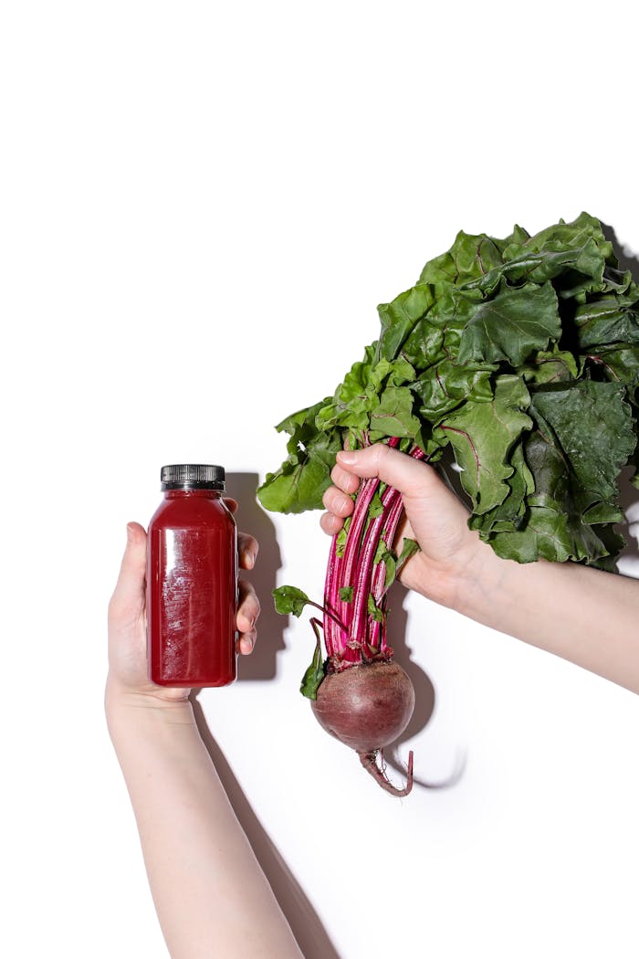 A hand holds fresh beetroot and juice bottle, showcasing healthy detox ingredients.